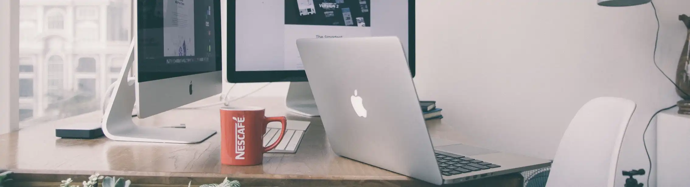 Macbook With Two Imac on Top of Table and Coffee